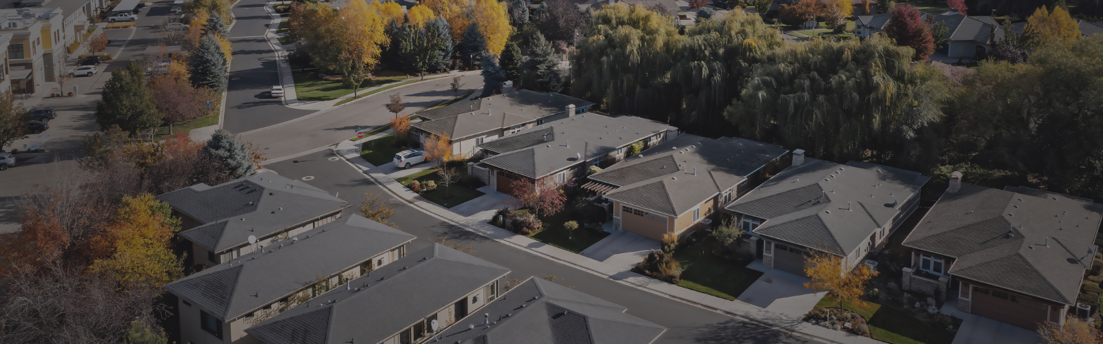 Aerial view of a residential neighborhood in Boise, Idaho, with modern homes, colorful fall trees, and scenic foothills in the background.
