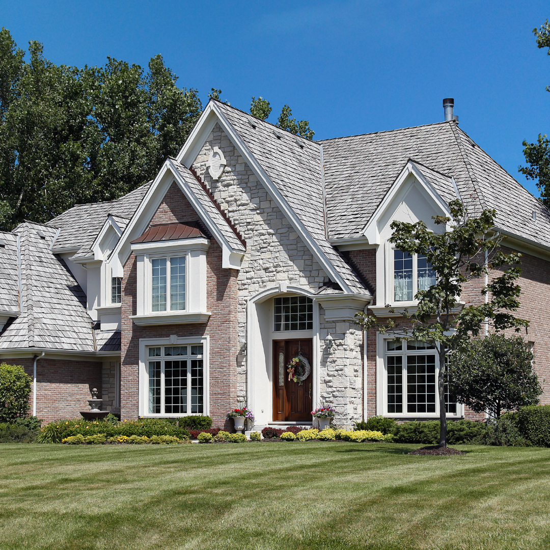 Luxury home with natural cedar shake roofing, featuring a mix of brick and stone siding and detailed architectural design.
