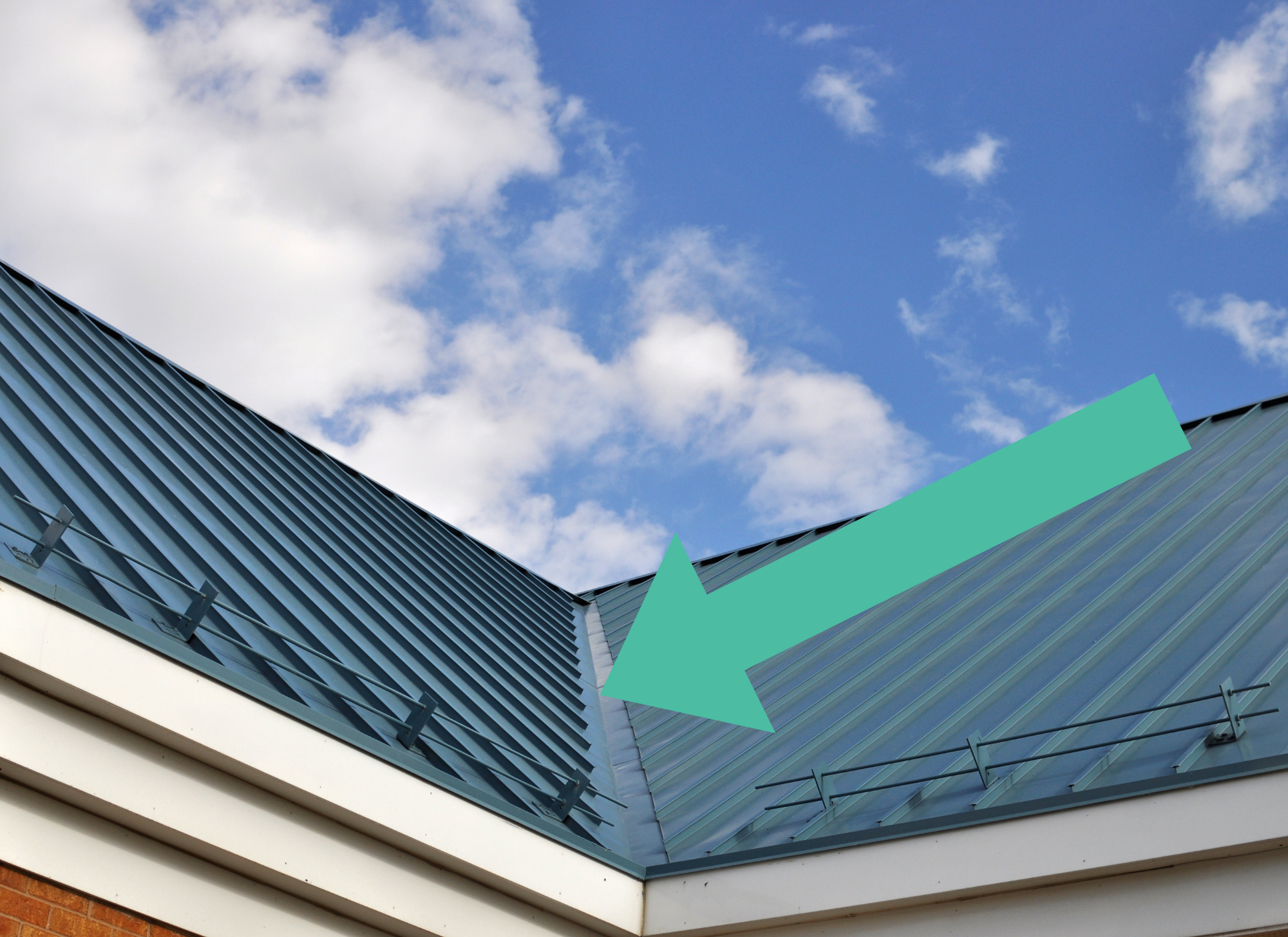 Blue standing seam metal roof with a metal valley flashing directing water runoff where two roof slopes meet.